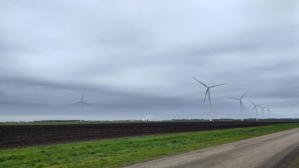Een aantal turbines van het windpark N33, met in de verte de witte stikstoffabriek bij Zuidbroek.