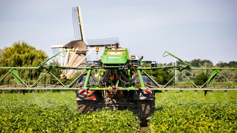 Een boer bij het dorp Heinenoord in Zuid-Holland bewerkt zijn akker met een bestrijdingsmiddel.