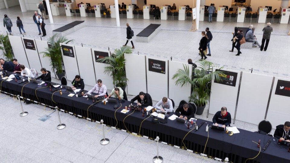 Hack the Hague 2022: hackers aan een lange rij tafels