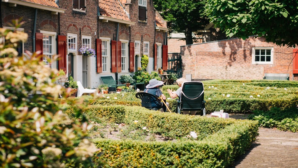 Twee ouderen zitten op stoelen in een tuin. Foto: Joyce Huis