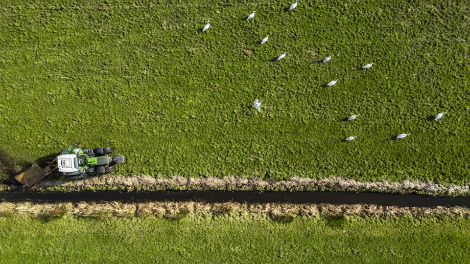 Een boer aan het werk op het land met zijn tractor, bij Westbroek in de provincie Utrecht.