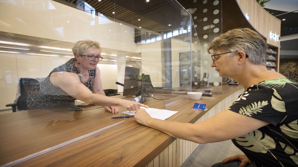 Een vrouw wordt geholpen bij een loket van het gemeentehuis. Foto: Joyce van Belkom (ANP)