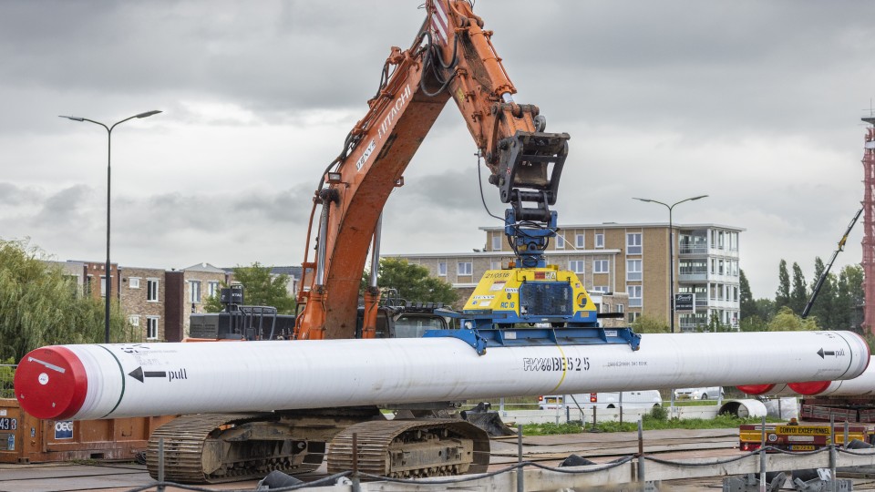 Een buis voor een warmtenet bij Rijswijk wordt in de grond gelegd.