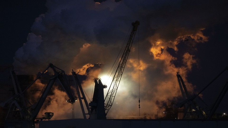 Een vlam van het affakkelen verlicht een uitgestoten stoomwolk op het Tata Steel terrein.