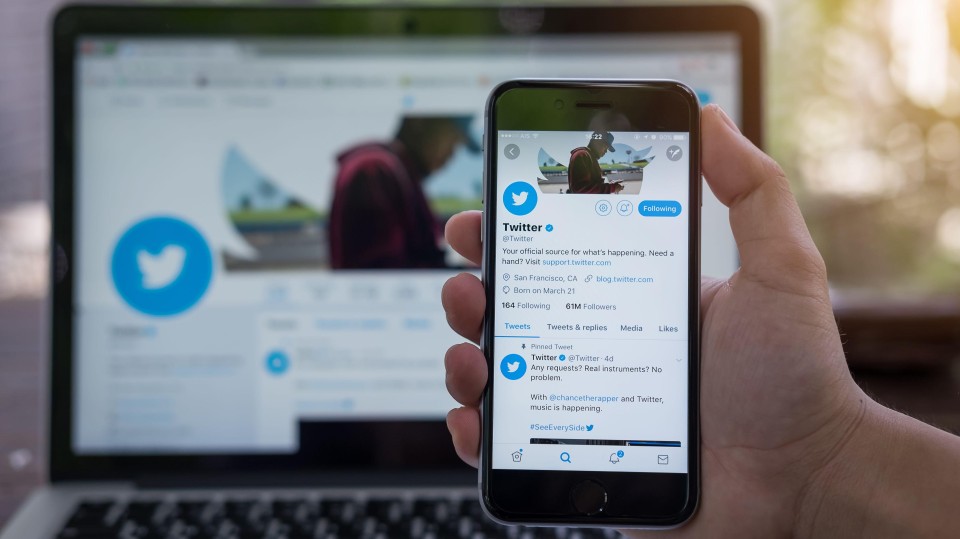 Laptop met Twitter en iphone in hand met Twitter op het scherm