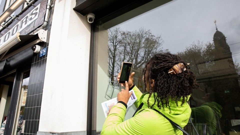 Vrouw maakt foto met haar telefoon van een veiligheidscamera