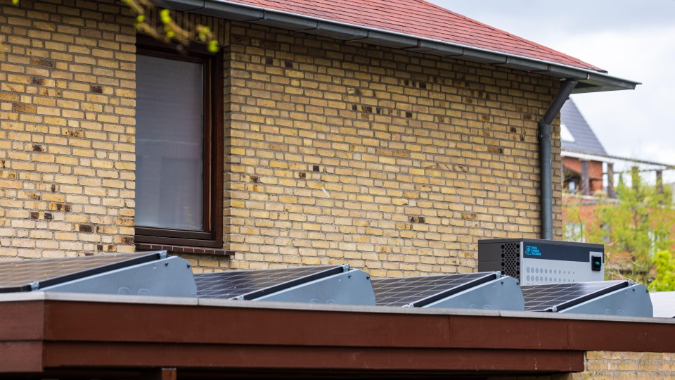 Een woning met zonnepanelen en een warmtepomp op het dak.