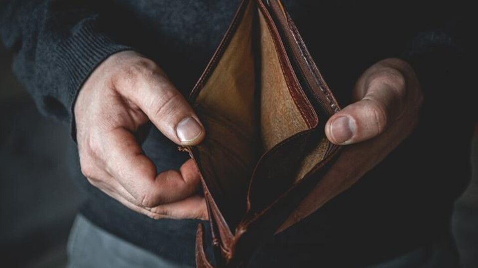 Handen houden een lege bruine leren portemonnee vast, zonder geld erin.
