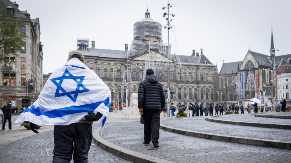 Man met Israëlische vlag over de schouders loopt over de Dam