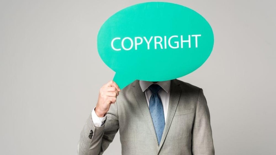 Man houdt bordje met 'copyright' voor gezicht
