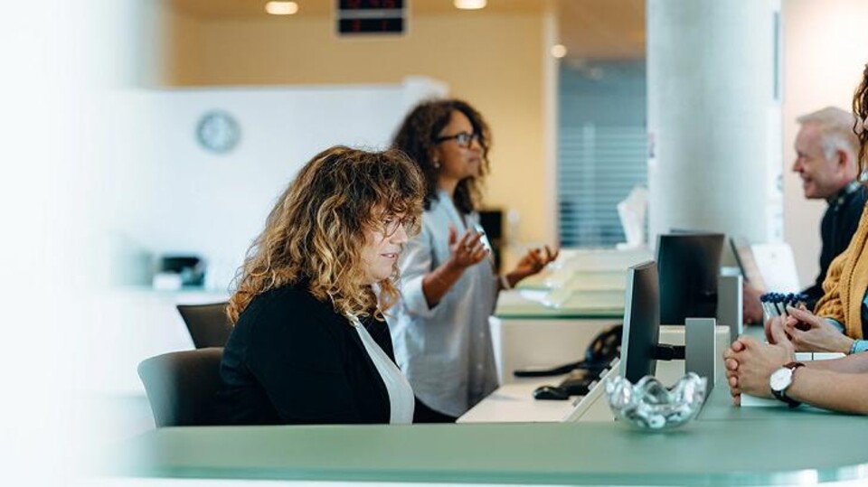 Een ambtenaar achter de balie helpt inwoners 