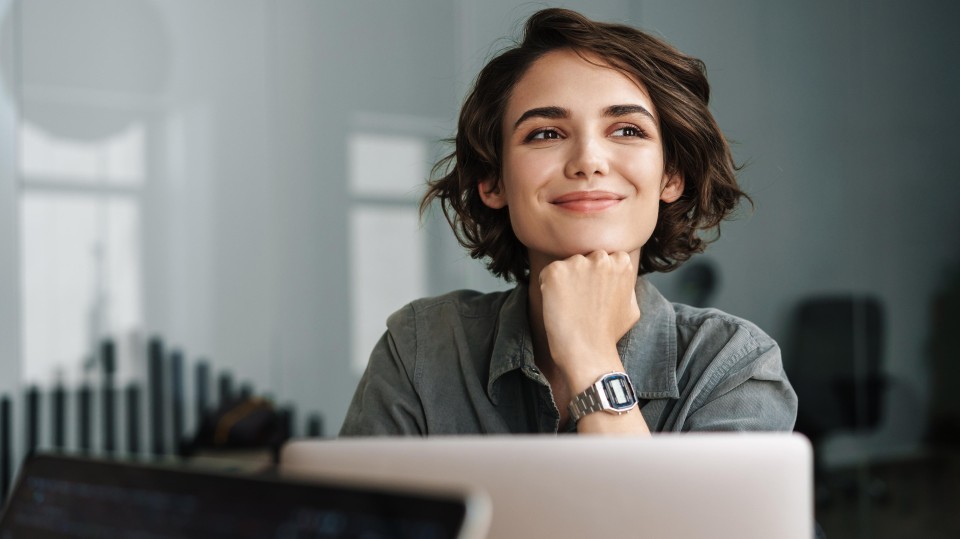 Jonge vrouw achter computer kijkt tevreden