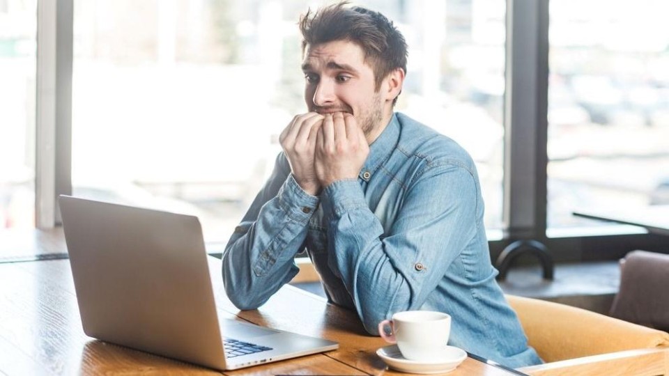 Angstige man staart naar laptopscherm