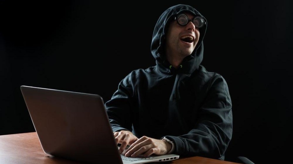 'hacker' in zwarte capuchontrui lacht