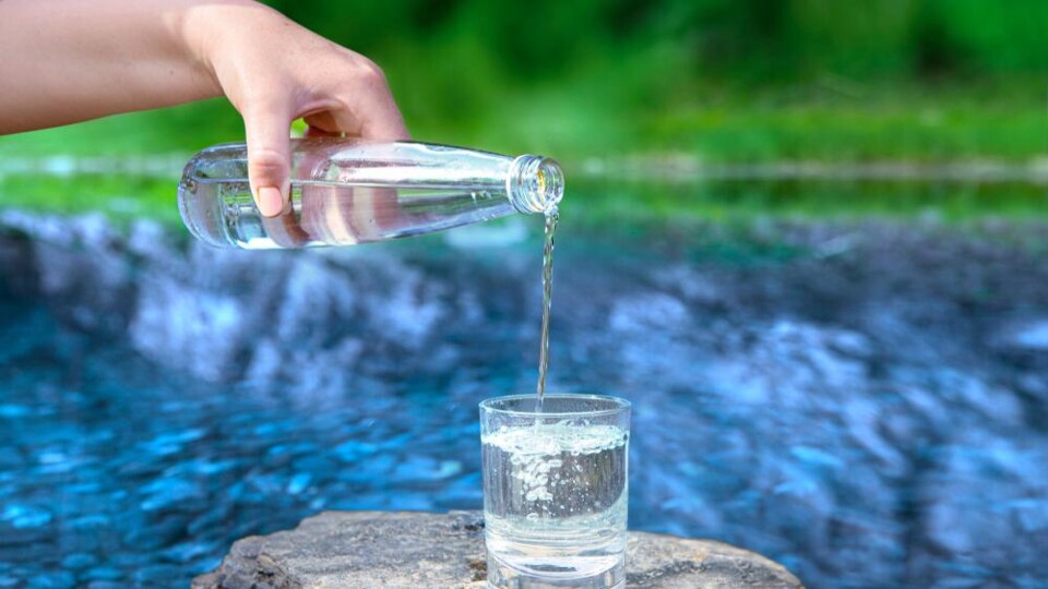 Hand schenkt water in voor rivier