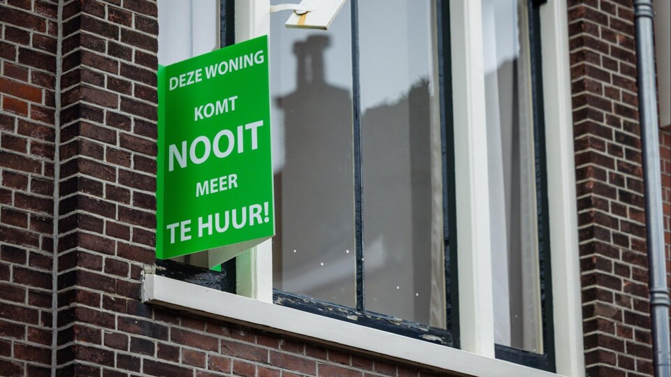 Groen bord aan gevel met tekst 'Deze woning komt nooit meer te huur' naast een raam van een bakstenen huis.