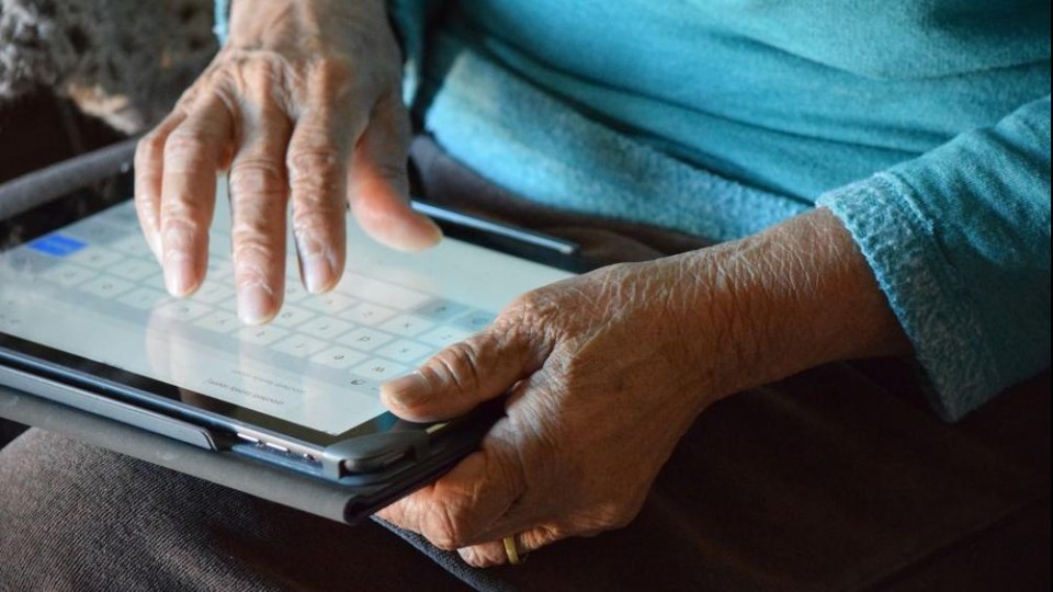 oude handen houden een tablet vast