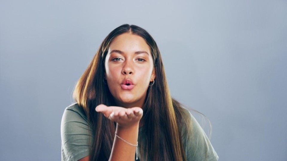 vrouw blaast kus naar lens