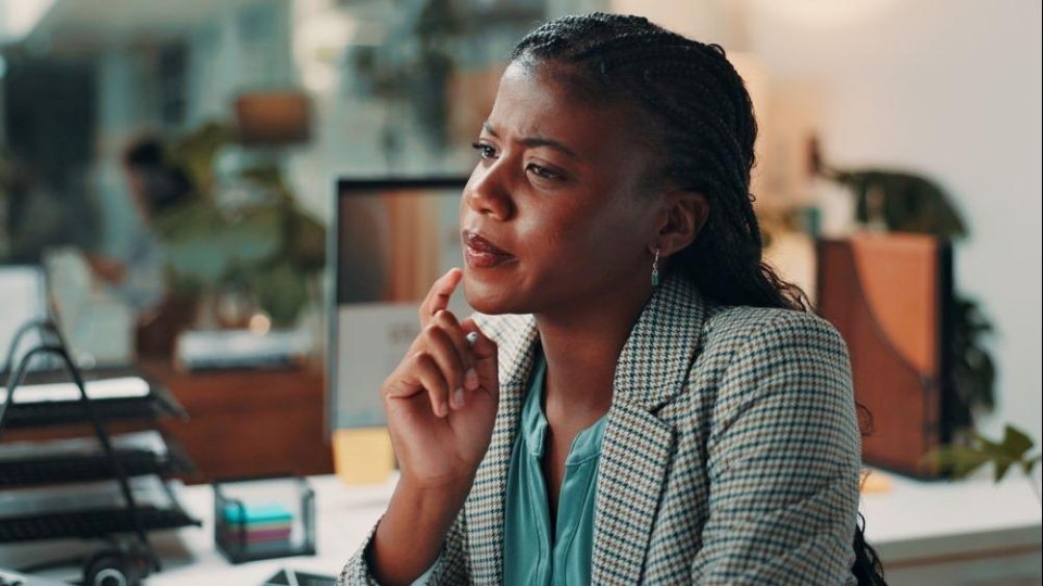 Jonge vrouw in kantoorsetting kijkt bedachtzaam