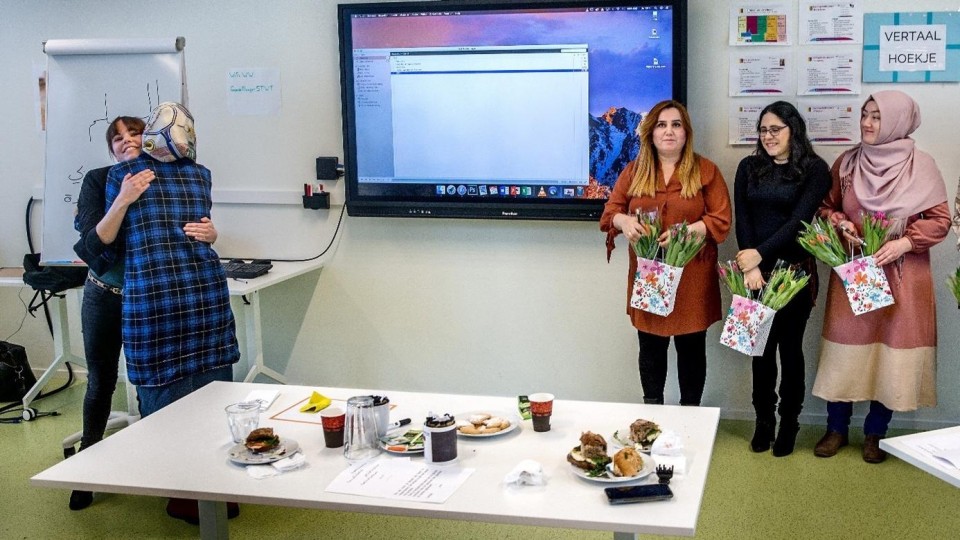 Statushouders vieren dat ze een cursus succesvol hebben doorlopen en hun een baan wordt aangeboden.