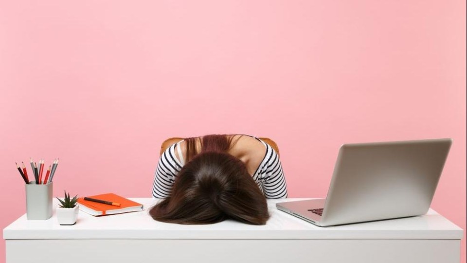 Meisje met haar hoofd op bureau naast laptop