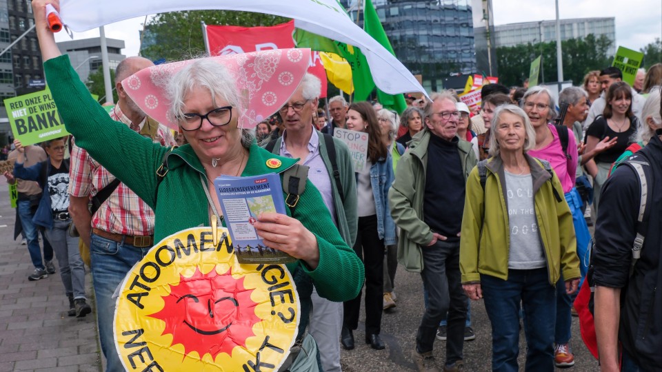 Tijdens een klimaatmars op de Zuidas in Amsterdam zwaait een vrouw met een klimaatvlag van de FNV, terwijl ze protesteert tegen…