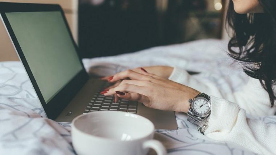 vrouw werkt op bed op laptop