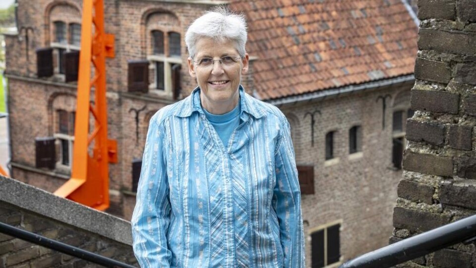 Constance Boogers in blauw-witte blouse op een trap buiten, met achter haar een historisch pand