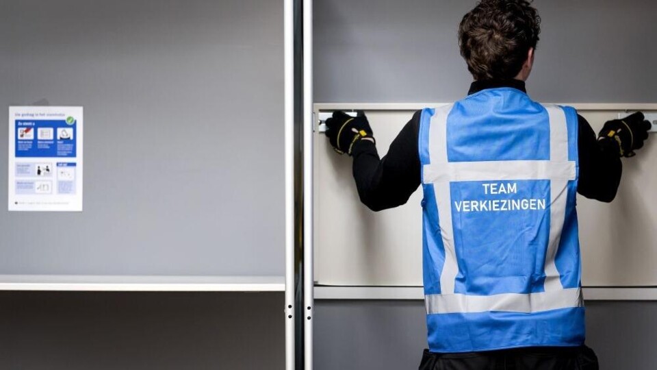 Een medewerker van de gemeente zet een stemhokje in elkaar