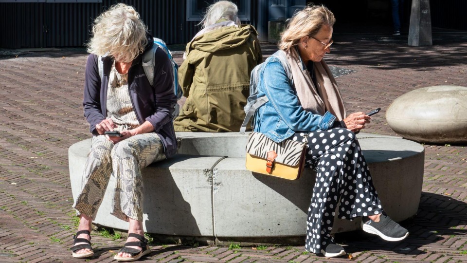 oudere vrouwen gebogen over hun smartphone