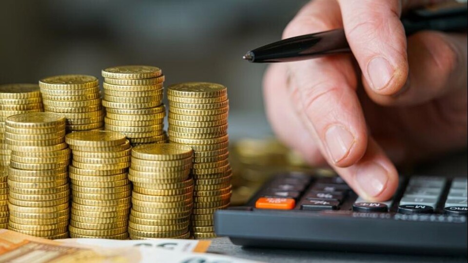 een stapel euromunten en -biljetten en een rekenmachine