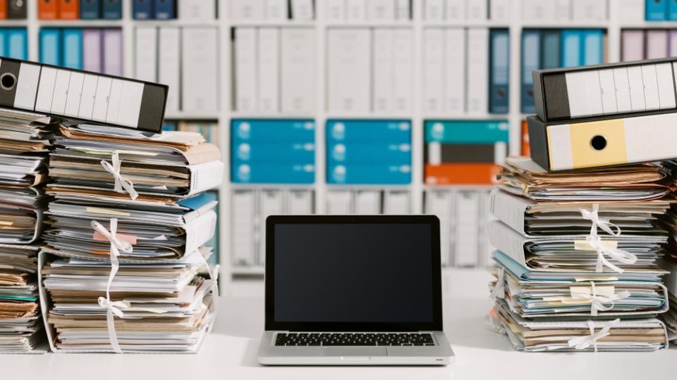 Laptop tussen stapels papieren mappen