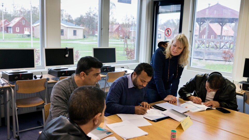 Vier mannen zitten aan een tafel en volgen een inburgeringscursus