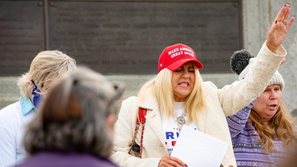Vrouw met MAGA-petje bid