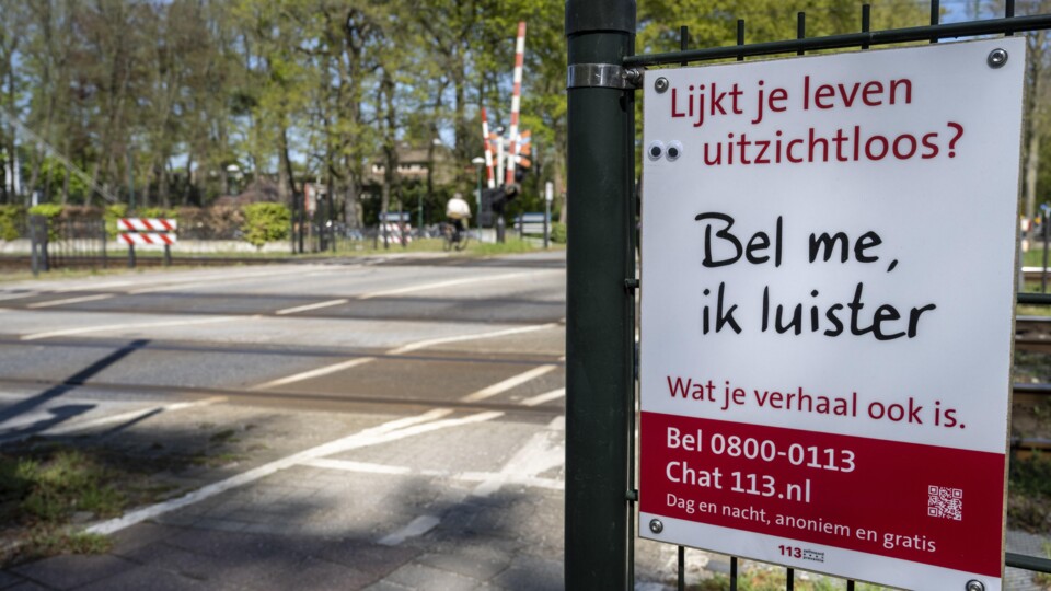 Een bord van stichting 113 Zelfmoordpreventie bij een spoorwegovergang
