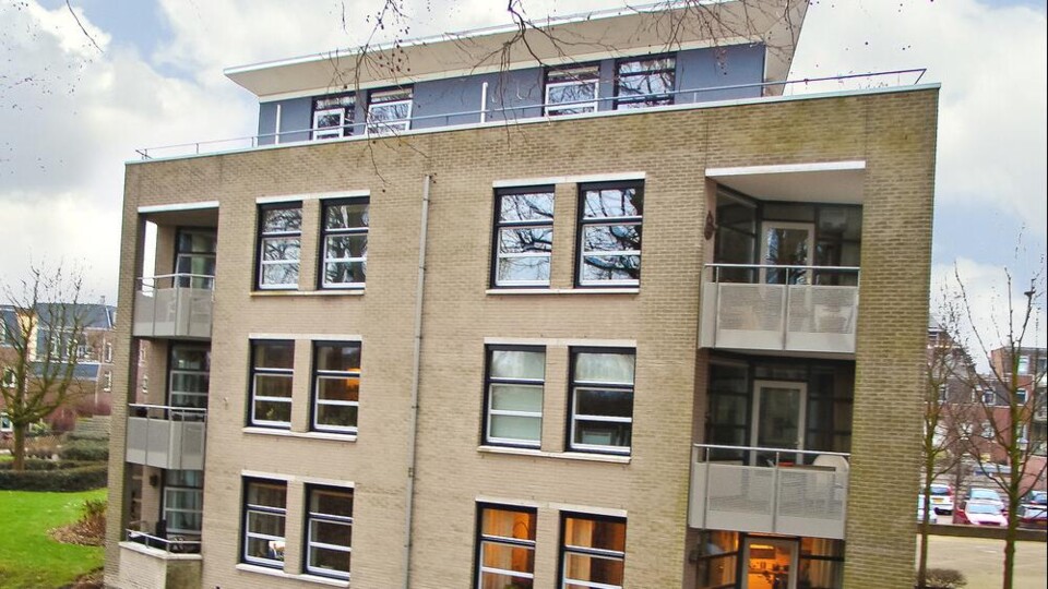 Woongebouw met meerdere verdiepingen en een extra woonlaag bovenop het dak, gelegen aan een waterpartij in Rotterdam.