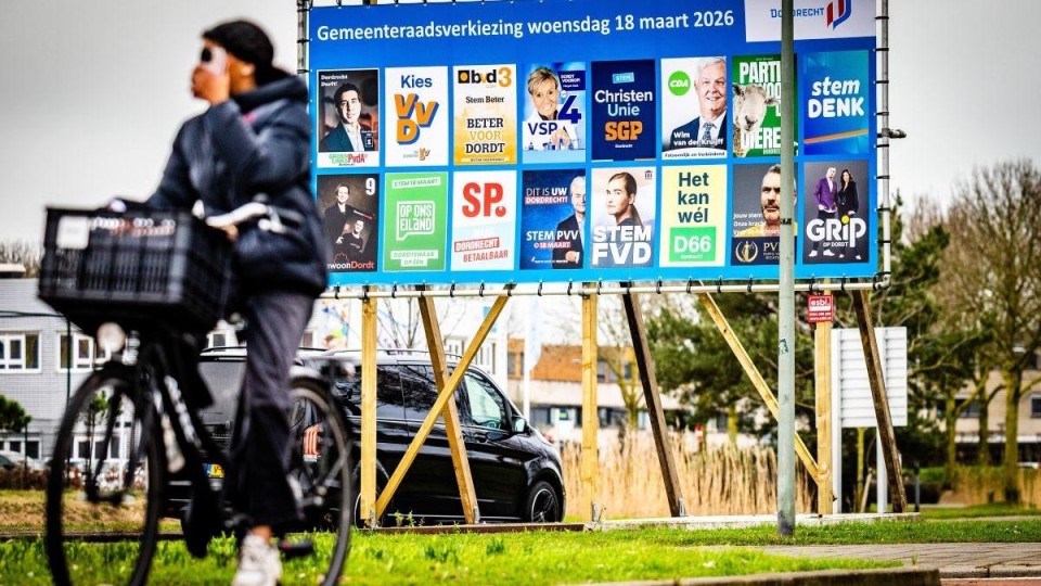 Fietser rijdt voorbij bord met verkiezingsposters