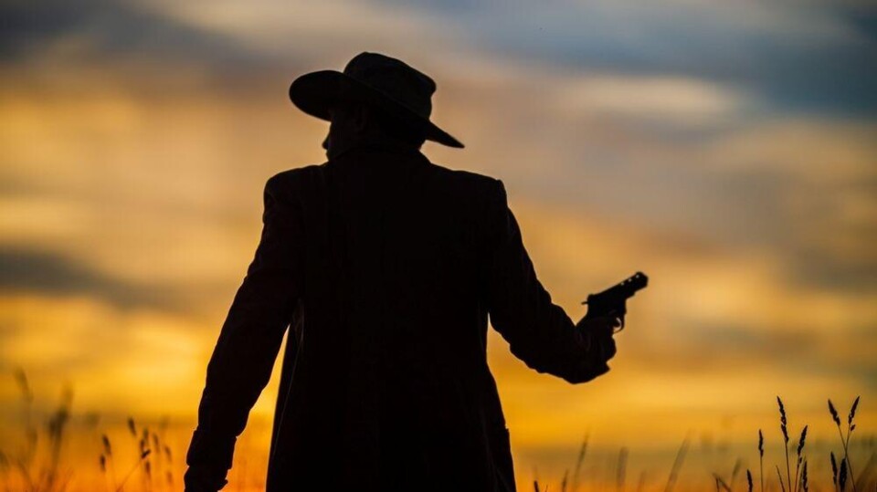 Silhouet van een cowboy met een getrokken pistool tegen een zonsondergang