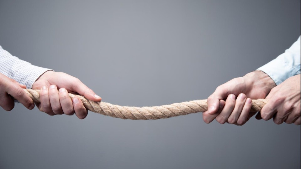 Twee mannenarmen in overhemd doen aan touwtrekken