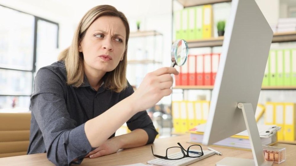 Vrouw kijkt naar computer met vergrootglas (?)
