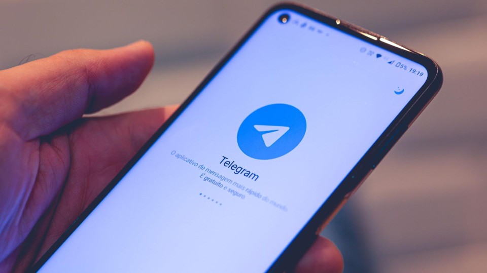 Hand met smartphone met logo Telegram op scherm