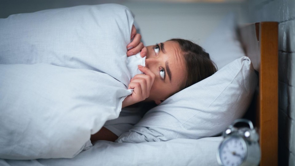 Vrouw ligt wakker met bang gezicht