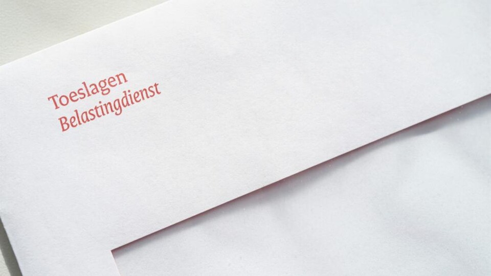 Witte envelop met rode tekst 'Toeslagen Belastingdienst' op een lichte achtergrond.