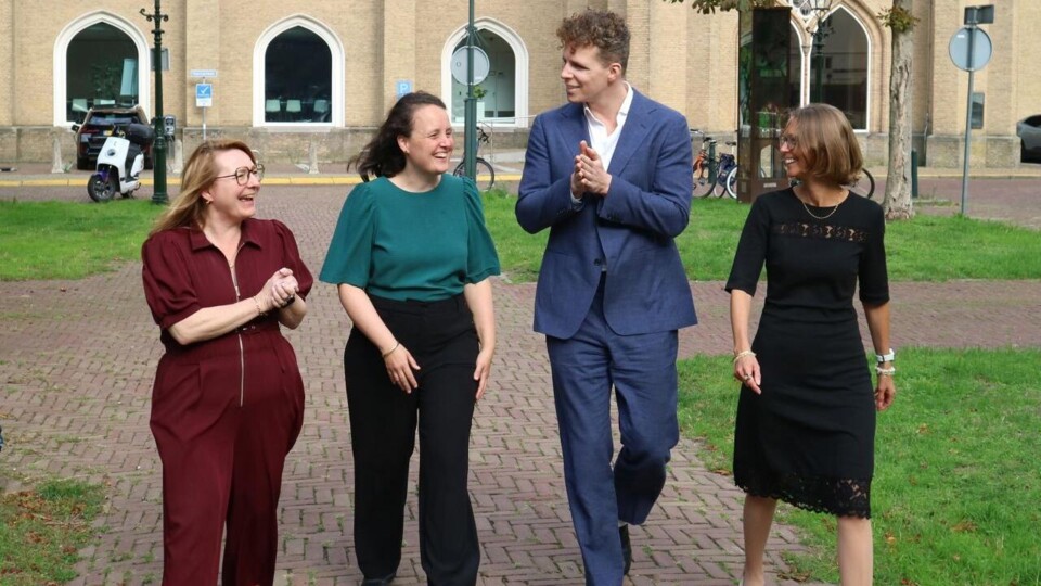 Drie vrouwen en een man, lachend, lopen buiten