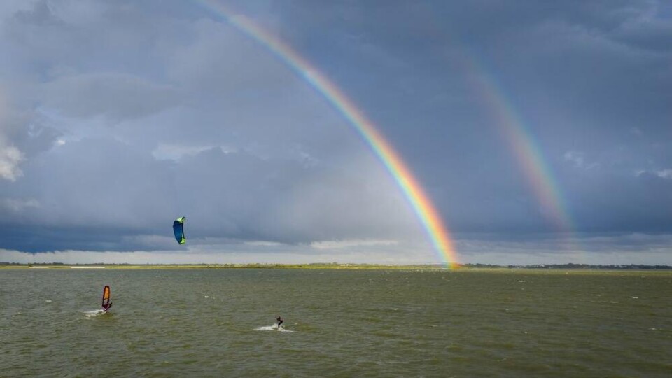 Surfers op het IJsselmeer, met een regenboogw