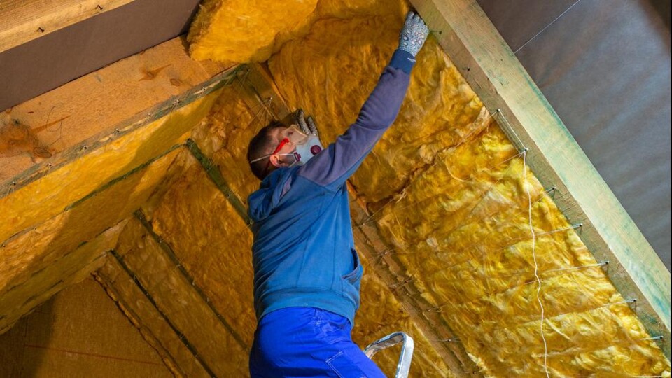 Man in blauwe trui isoleert een puntdak